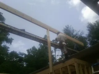 Carpenter setting a ridge beam over a new addition frame — Ice Dam Removal by Roofing Brothers in Holmesville