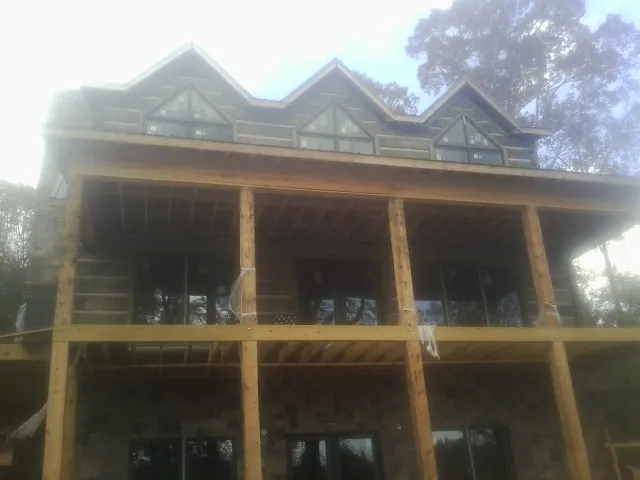 Dormers and porch framing on a large log home under construction — Roof Coating work by our crew in Holmesville