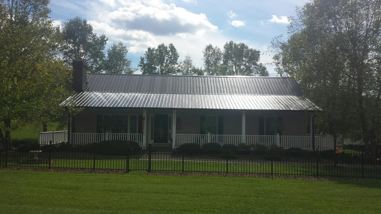 Gray metal roof on a brick ranch with a full width front porch — Gutter Guard Installation work by our crew in Holmesville