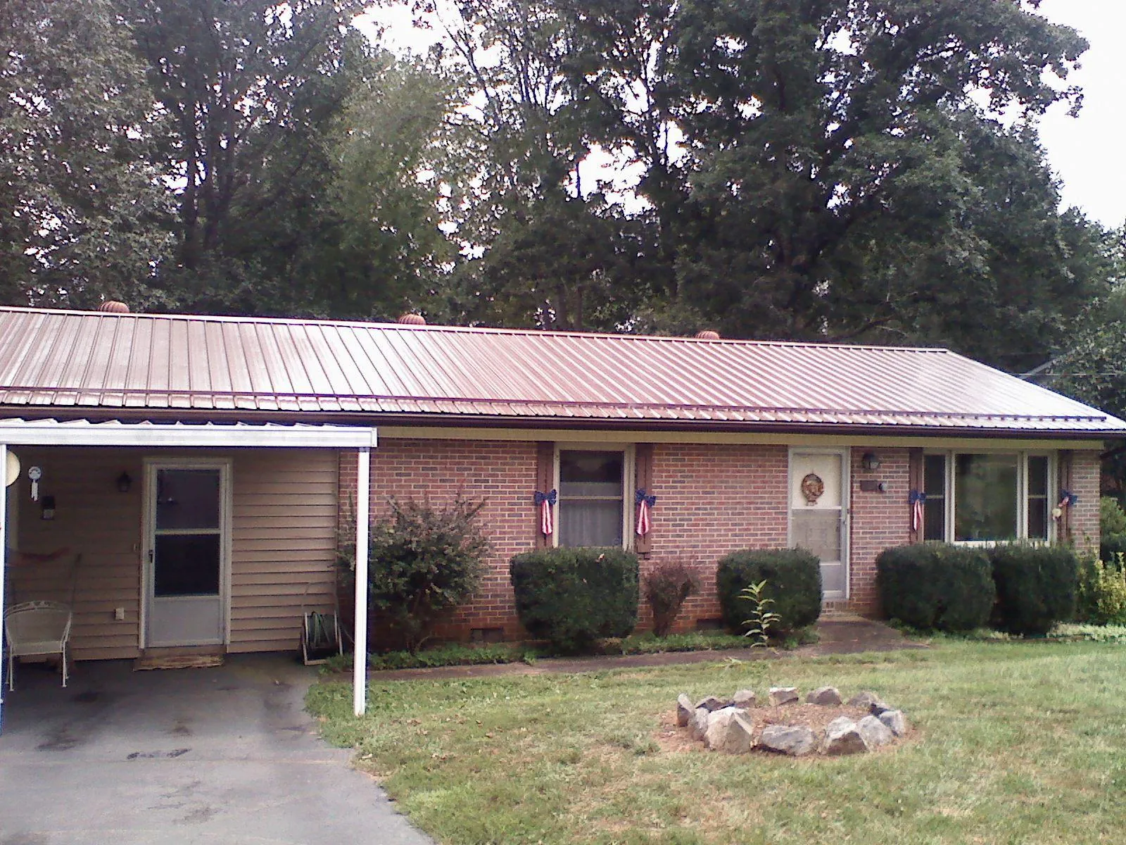 Bronze metal roof and carport on a brick ranch home — Roof Repair work by our crew in Holmesville