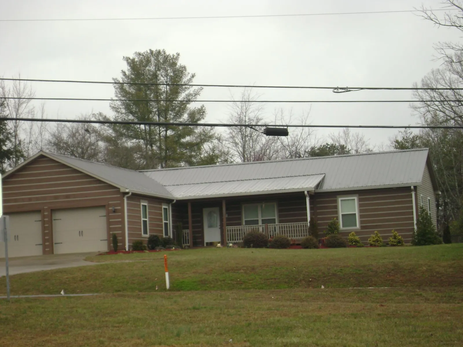 Gray metal roof on a log sided ranch home with a front porch in Holmesville
