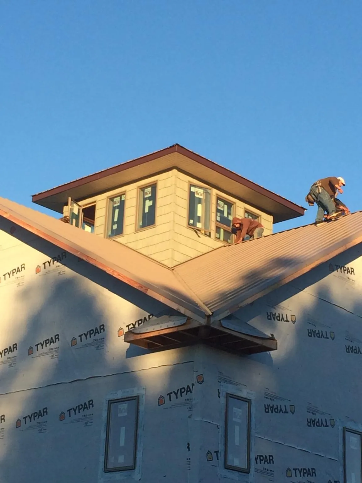 Roofers working around a rooftop cupola on a new metal roof at sunset — Roof Waterproofing in Holmesville by Roofing Brothers